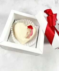Caja de regalo individual con corazón de chocolate blanco decorado y lazo rojo satinado, detalle romántico de Piel Canela.