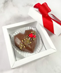 Caja de regalo individual con corazón de chocolate de leche decorado con oro y corazones rojos, detalle clásico de Piel Canela.
