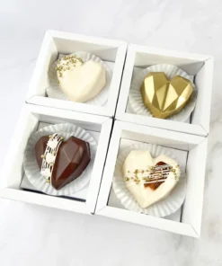 Set de cajas individuales Mini Amore con corazones geométricos de chocolate decorados en oro, blanco y chocolate oscuro.